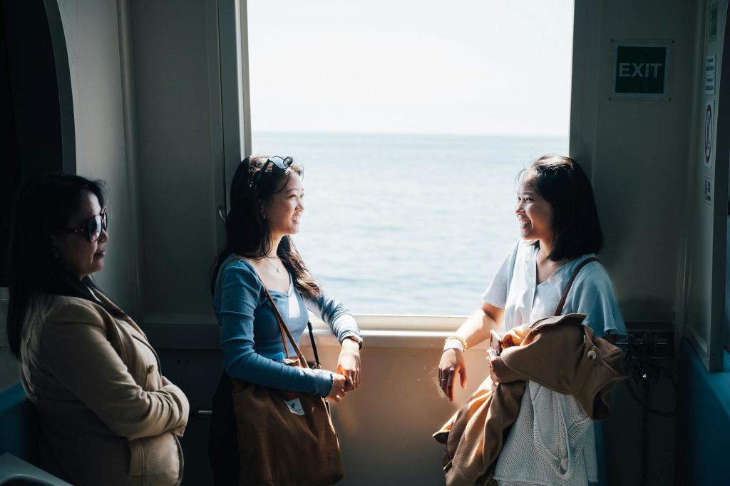 자연 채광 아래에서 바다가 보이는 창가에서 세 명의 여성이 이야기를 나누고 있습니다.