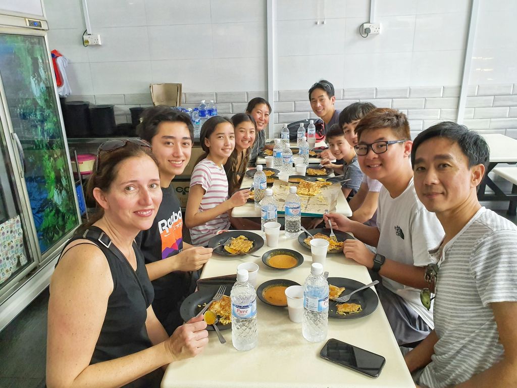 음식 접시, 물병, 수프 그릇이 놓인 식탁에서 미소를 짓는 사람들의 모임.