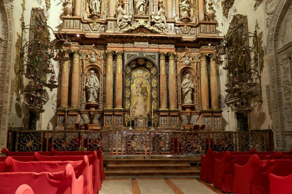 조각상, 정교한 조각품, 빨간색으로 덮인 의자가 있는 화려한 교회 제단입니다.