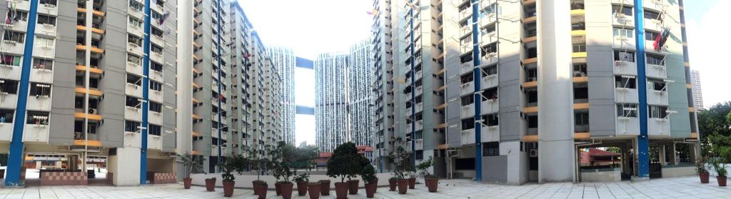 높은 아파트 건물은 커다란 화분이 있는 안뜰을 둘러싸고 있습니다. 배경 건물에는 스카이 브리지가 연결되어 있습니다.