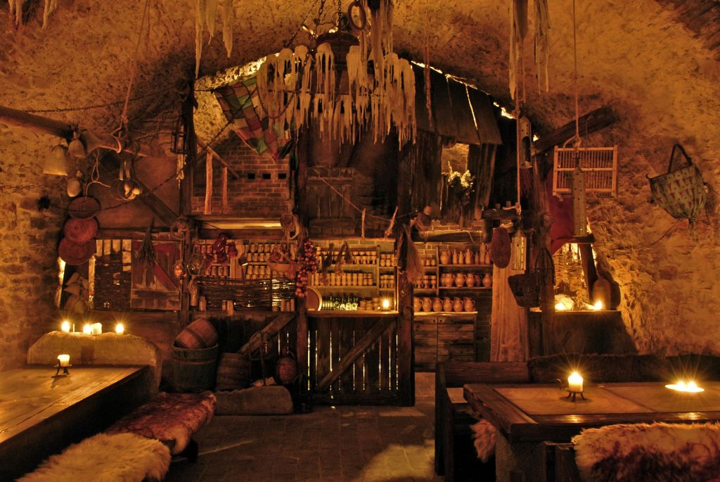 나무 가구, 걸이식 장식, 선반에 놓인 도자기, 따뜻한 빛을 발하는 촛불이 있는 희미한 소박한 방.