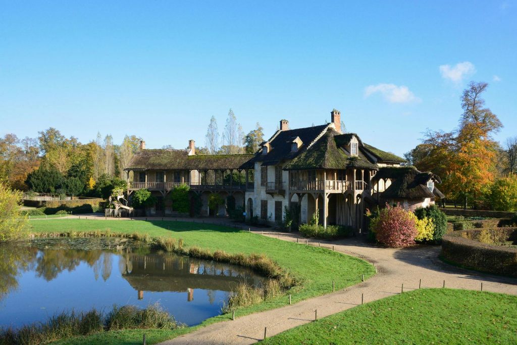 맑고 푸른 하늘 아래 녹음과 나무로 둘러싸인 연못 옆에 초가 지붕이 있는 독특한 건물입니다.