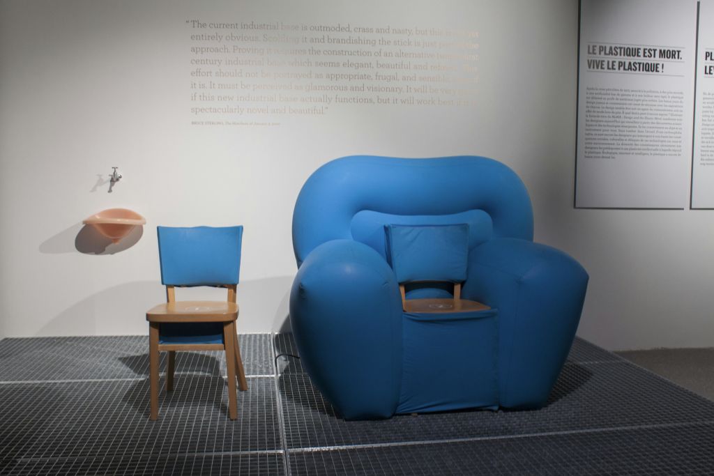 두 개의 의자: 희미한 글씨가 있는 벽에 작은 파란색 나무 의자와 더 큰 파란색 패딩 안락의자.