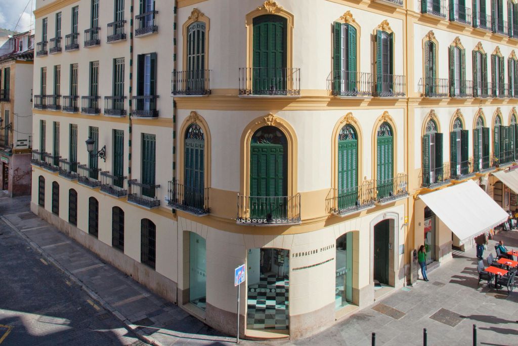 녹색 창문, 거리 수준의 아치형 출입구, 화려한 건축 디테일이 돋보이는 베이지색 건물의 모퉁이.