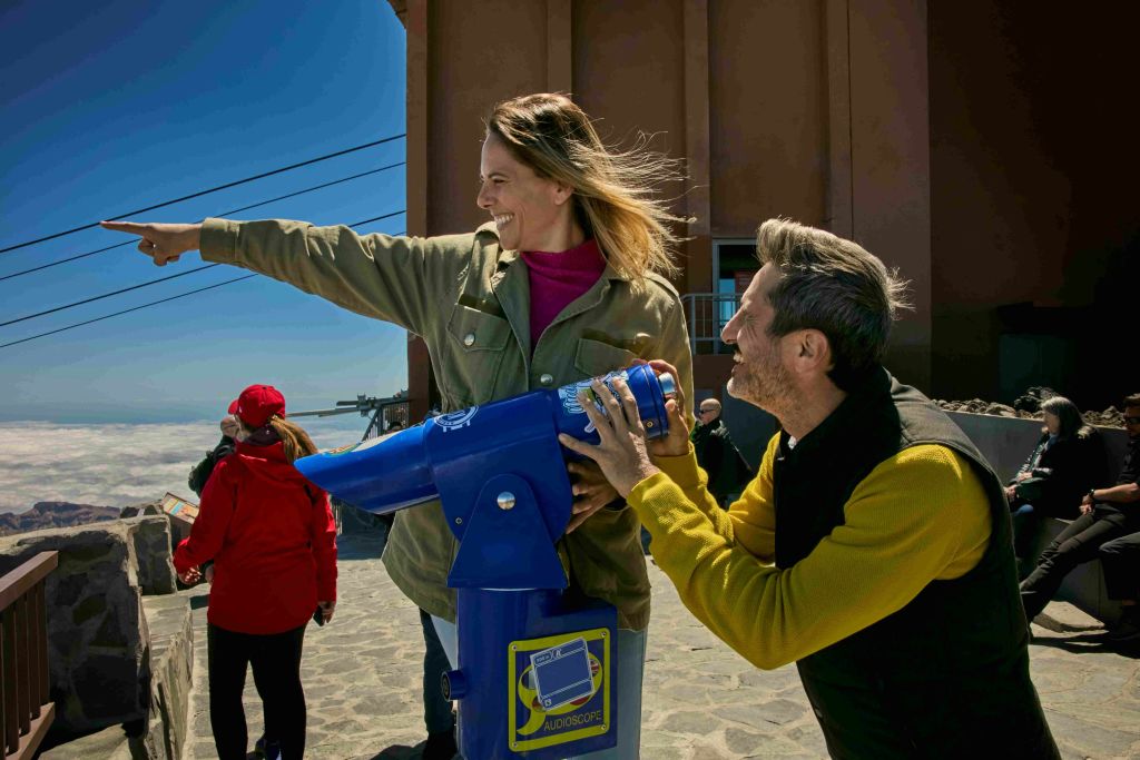 화창한 날 푸른 망원경을 사용하며 웃고 있는 남녀를 배경으로 다른 사람이 등장합니다.