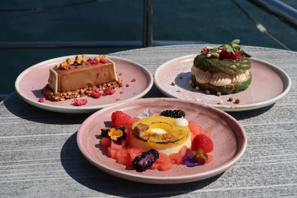 다채롭고 정교하게 배열된 식재료가 특징인 고급 디저트 3판이 나무 테이블에 놓여 있습니다.