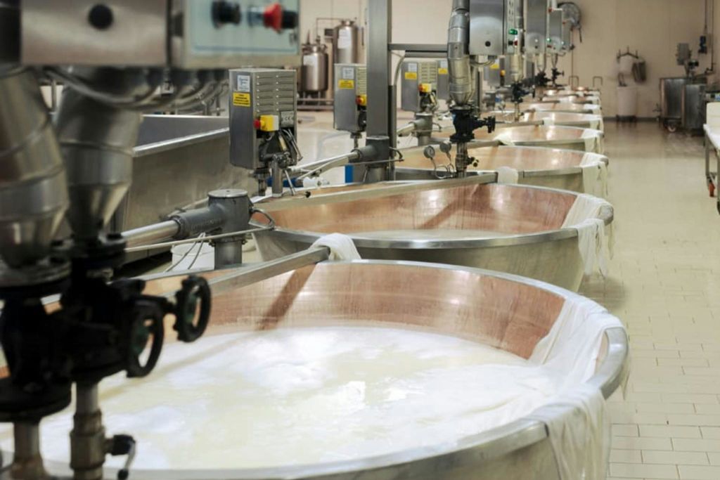 컨테이너 위에 여러 개의 기계와 파이프가 있는 산업 환경에서 액체로 채워진 대형 금속 통.