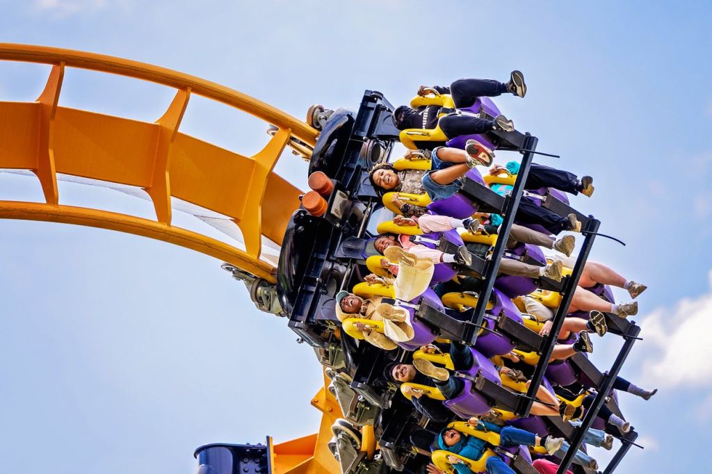 식스 플래그스 (Six Flags) 의 롤러코스터를 탄 사람들은 손을 번쩍 들고 파란색 면이 있는 트랙을 내려갑니다.