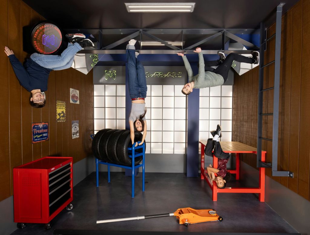 공구, 타이어, 자동차 인테리어가 돋보이는 차고 테마의 방에 4명이 거꾸로 매달려 있는 것으로 보입니다.