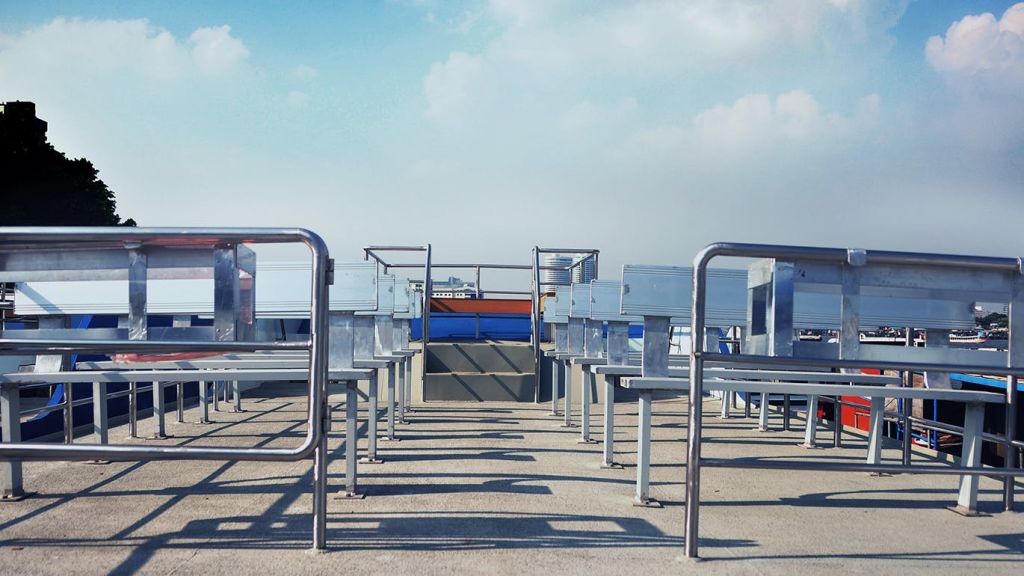 맑고 푸른 하늘 아래, 금속 벤치와 테이블이 줄지어 있는 빈 야외 파티오 좌석.