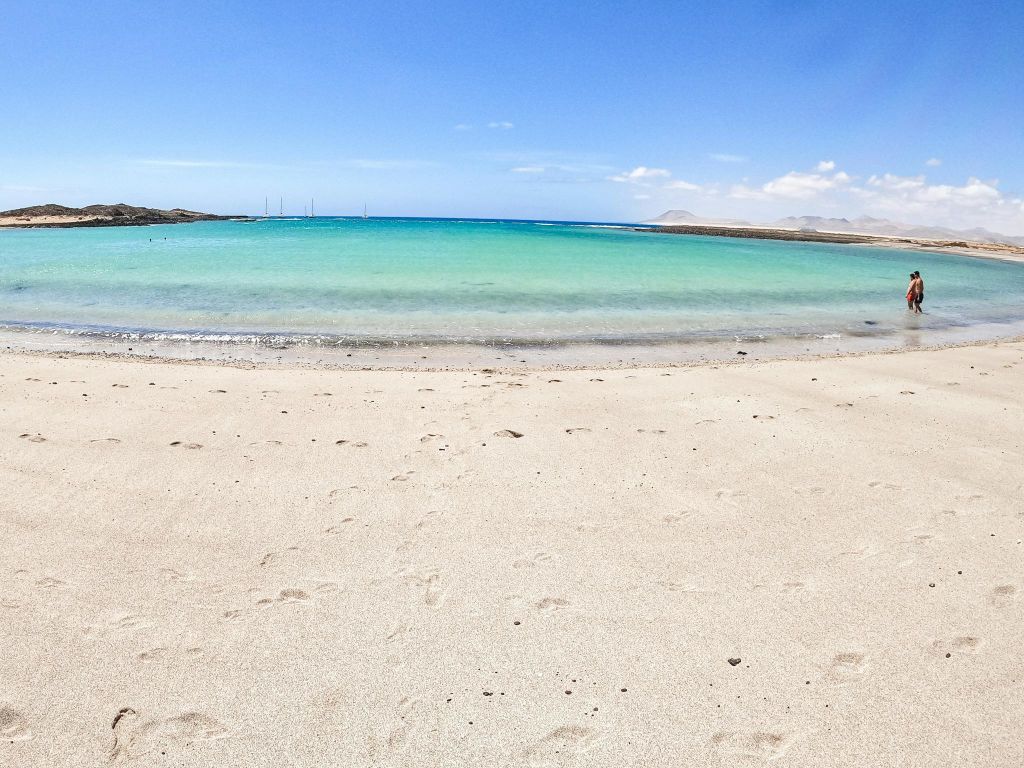 매끄러운 모래, 맑은 청록색 물, 밝은 구름이 있는 밝고 푸른 하늘이 있는 고요한 해변.