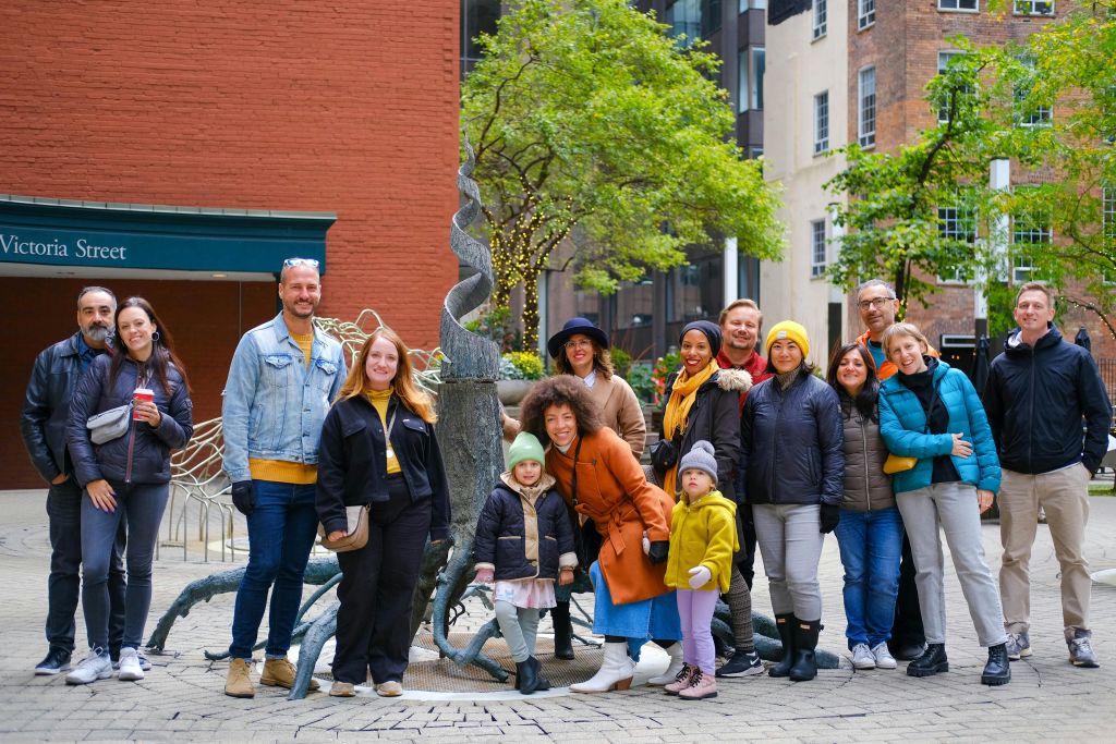 벽돌 건물과 나무를 배경으로 야외에서 함께 포즈를 취하는 사람들.