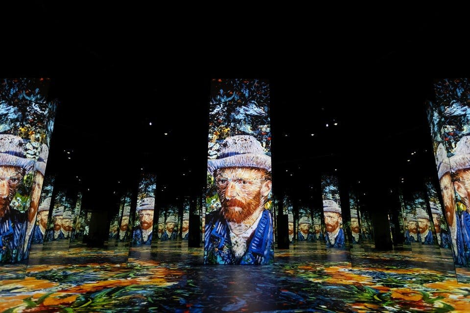 반 고흐의 자화상을 여러 개의 기둥에 투영한 어둡고 몰입감 넘치는 전시 공간에서 다채로운 바닥 패턴을 감상할 수 있습니다.