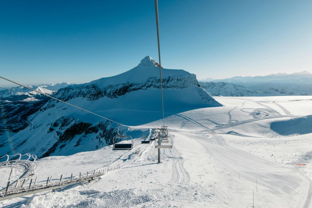 스키 리프트, 빈 의자, 맑고 푸른 하늘이 있는 눈 덮인 산. 스키 트랙은 아래 눈 속에서 볼 수 있습니다.