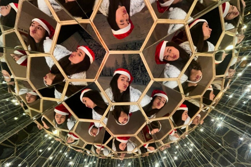 산타 모자를 쓴 사람은 기하학적 거울 구조에 여러 번 반사되어 만화경 효과를 냅니다.
