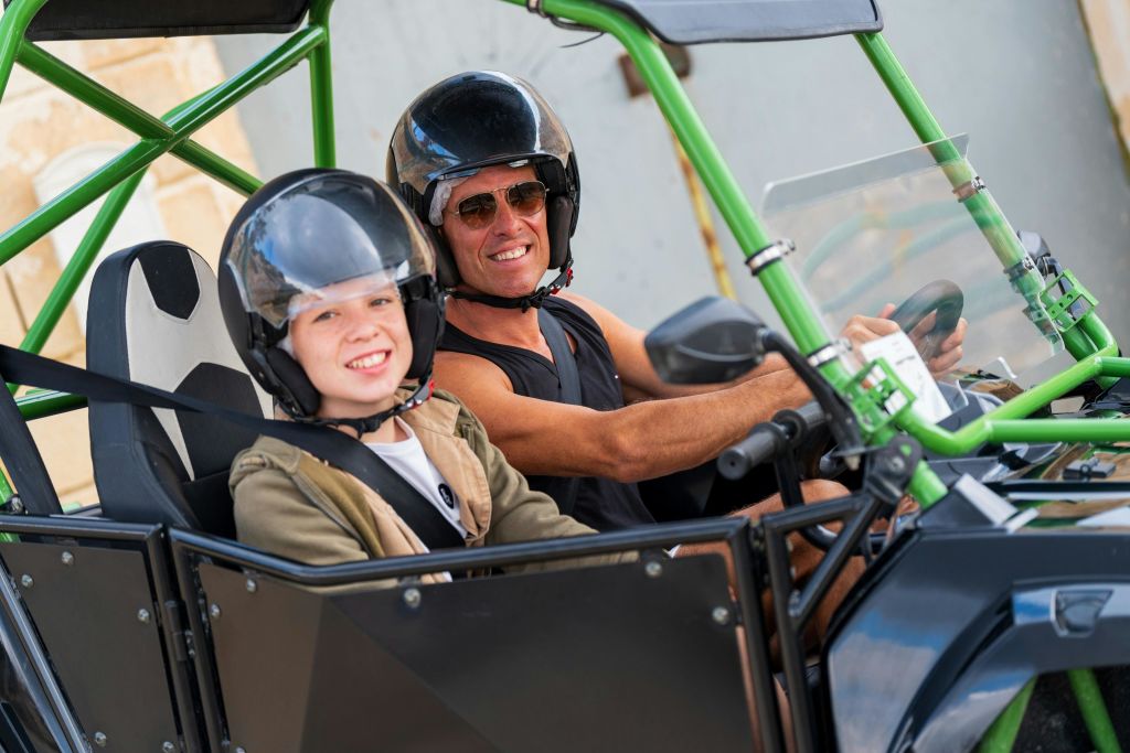 헬멧을 쓴 두 사람이 오프로드 차량에 앉아 웃으며 그 순간을 즐기고 있습니다.