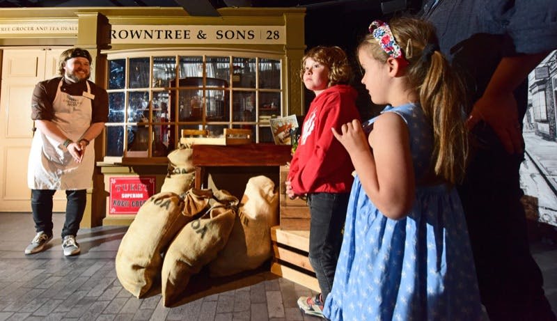 자루와 나무 상자가 있는 상점 앞에 두 명의 어린이가 서 있습니다.