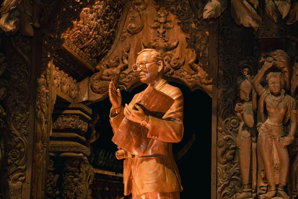 정교한 장식 조각으로 둘러싸인 문서를 들고 있는 남자의 정교하게 조각된 목조 동상.