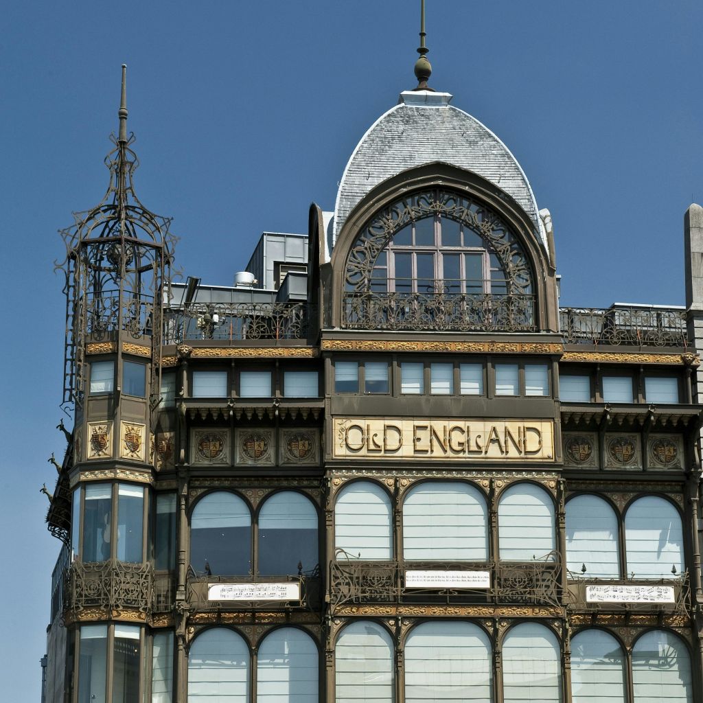 화려한 철공예품, 아치형 창문, 맑고 푸른 하늘 아래 '올드 잉글랜드' 라는 간판이 있는 유서 깊은 건물입니다.