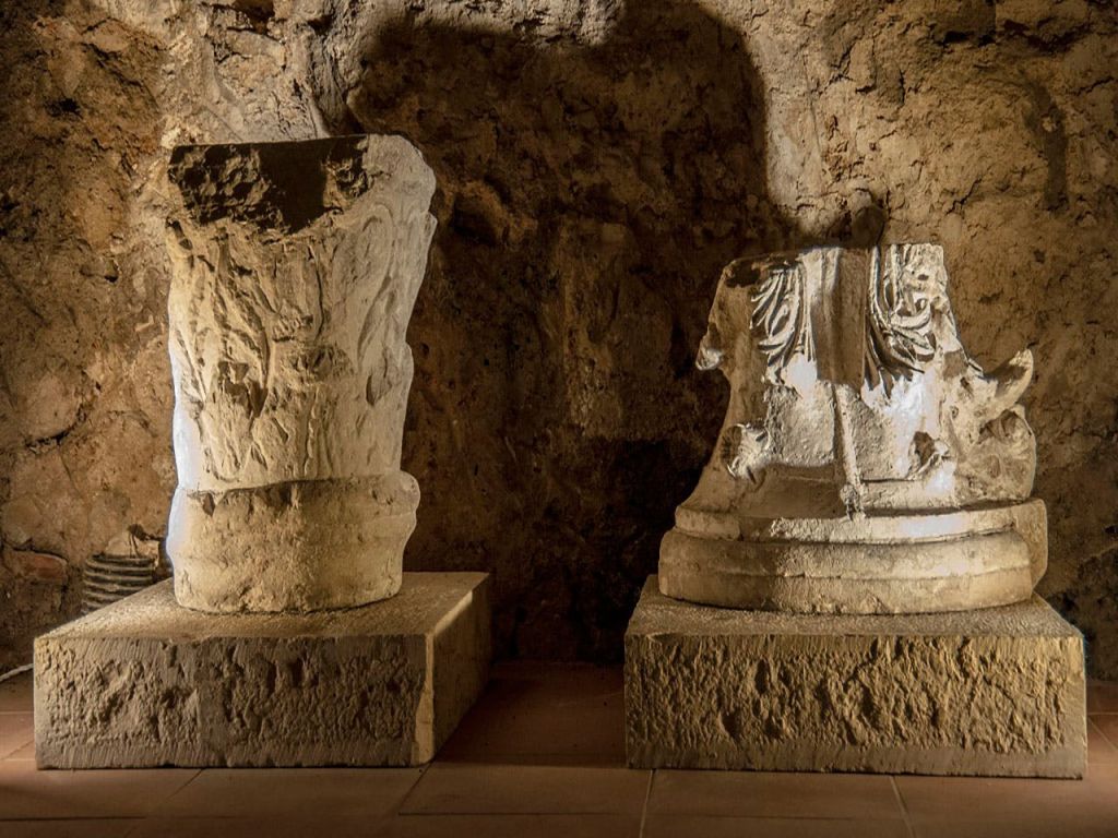 조명이 희미하고 바위가 많은 동굴 환경에 두 개의 고대 석상이 전시되어 있습니다.