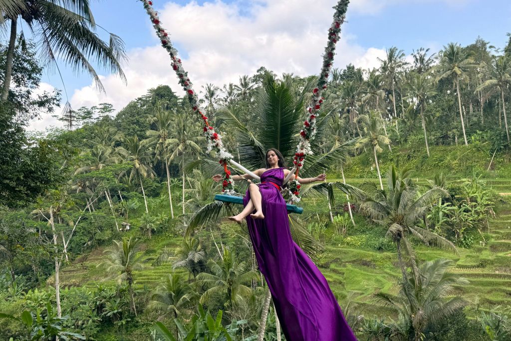 U 펀 필드에서 플라워 스윙을 즐기는 보라색 드레스를 입은 여성