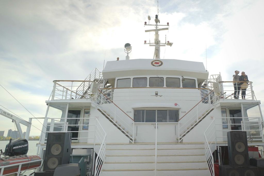 오두막으로 이어지는 계단과 안테나 및 조명과 같은 눈에 띄는 구조물이 있는 배의 상부 갑판. 위에 흩어진 구름이 있는 하늘.