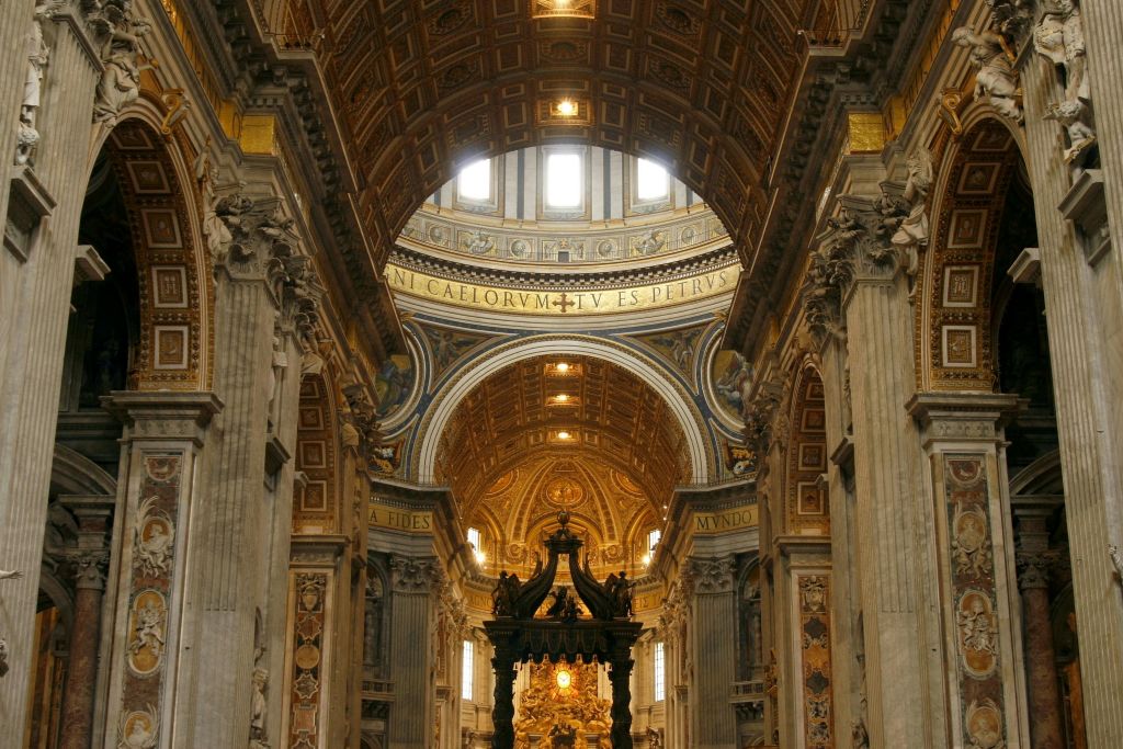 금빛 돔, 기둥, 종교적 문구가 새겨진 대성당의 화려한 내부. 중앙에는 검은 제단이 서 있습니다.