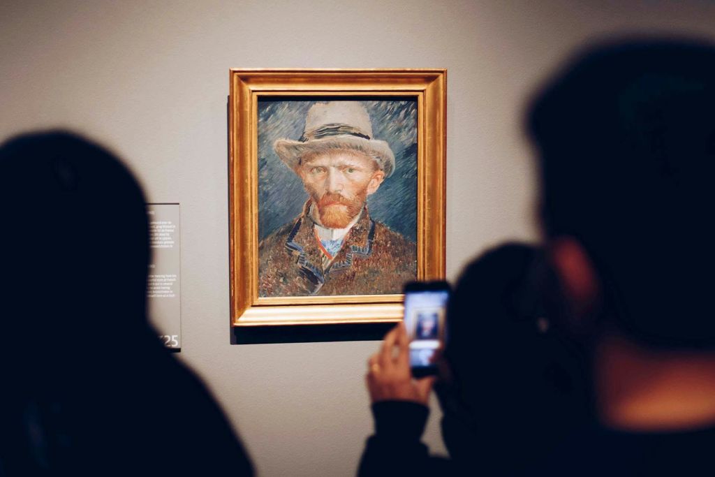 모자를 쓴 남자의 액자 그림이 벽에 전시되어 있으며, 시청자들은 앞면에 모자를 쓰고 사진을 찍습니다.