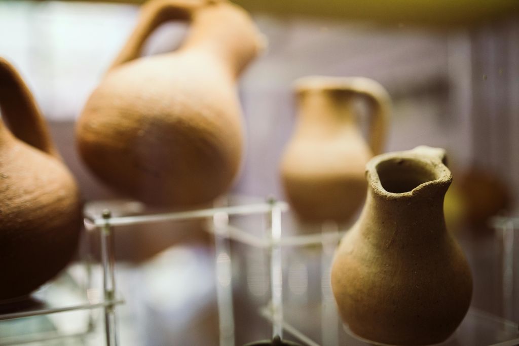 박물관의 투명 스탠드에 세 개의 고대 점토 주전자가 전시되어 있습니다.