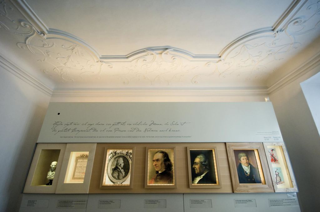 전시품 위쪽에 장식 문구가 있는 화려한 천장 아래 박물관에 전시된 작품과 초상화.