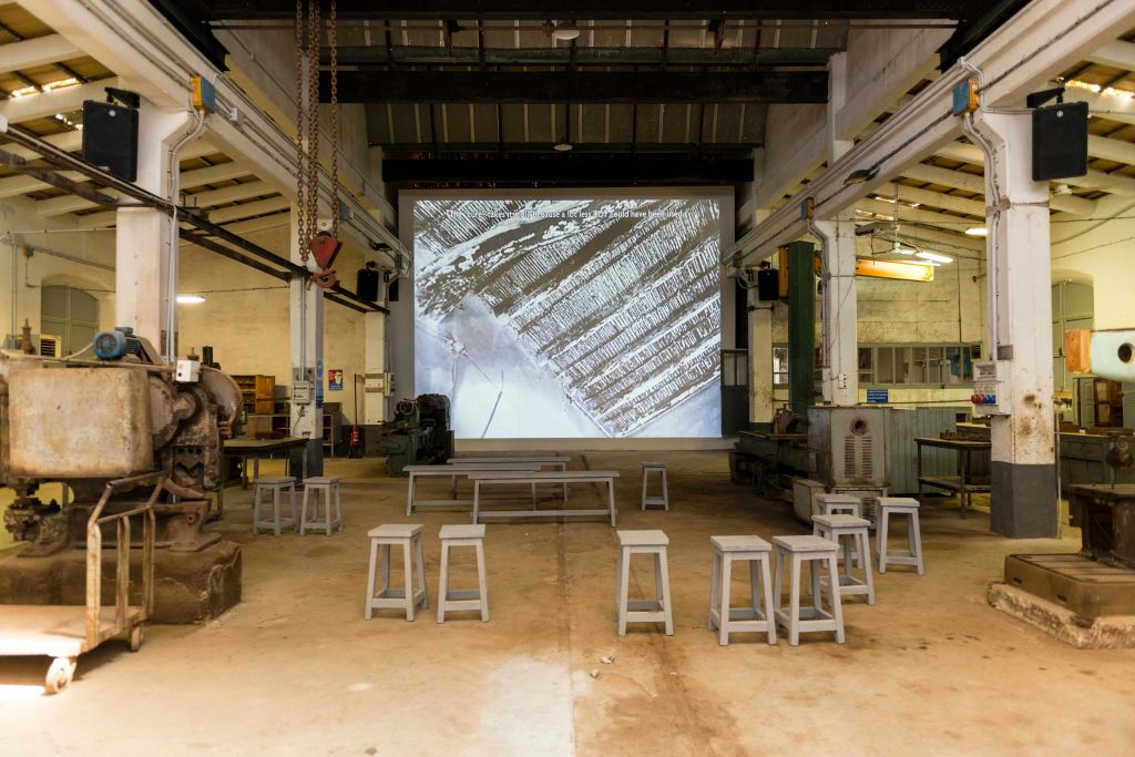 설원의 공중 전망을 감상할 수 있는 대형 스크린 앞에 스툴이 배치된 넓은 산업용 객실.