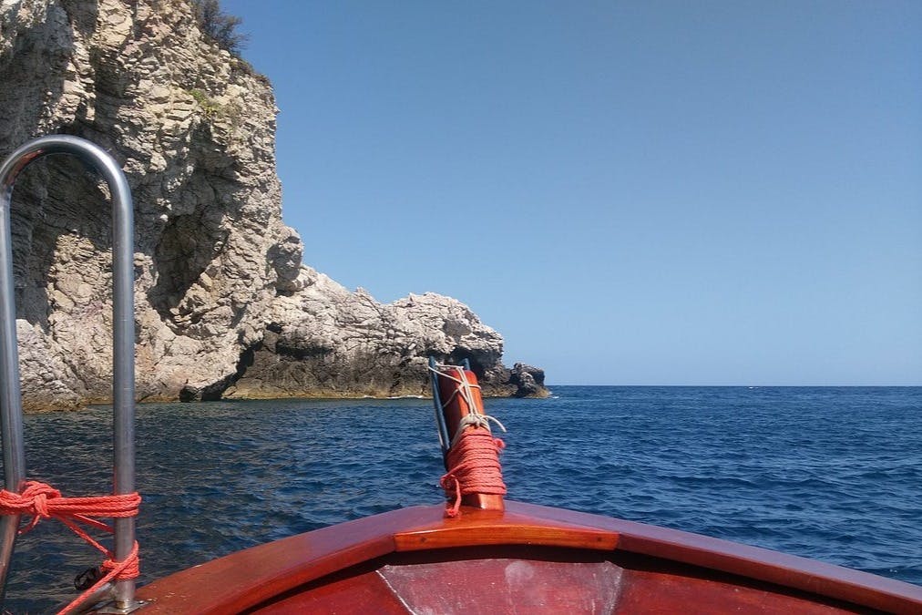 맑고 푸른 물 위로 바위 절벽으로 접근하는 보트의 활에서 머리 위로 맑은 하늘이 내려다보이는 풍경.