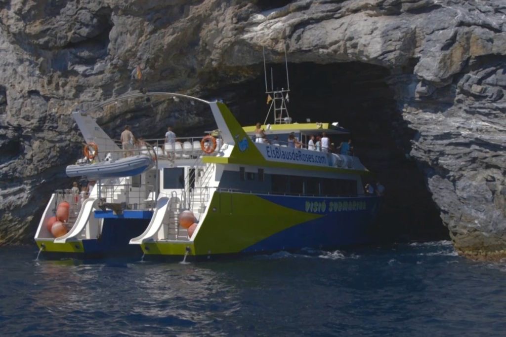 Catamarás de visión submarina Aquarium II entrando en la cueva de Tamariu, Cap Norfeu parc natural Cap de Creus.