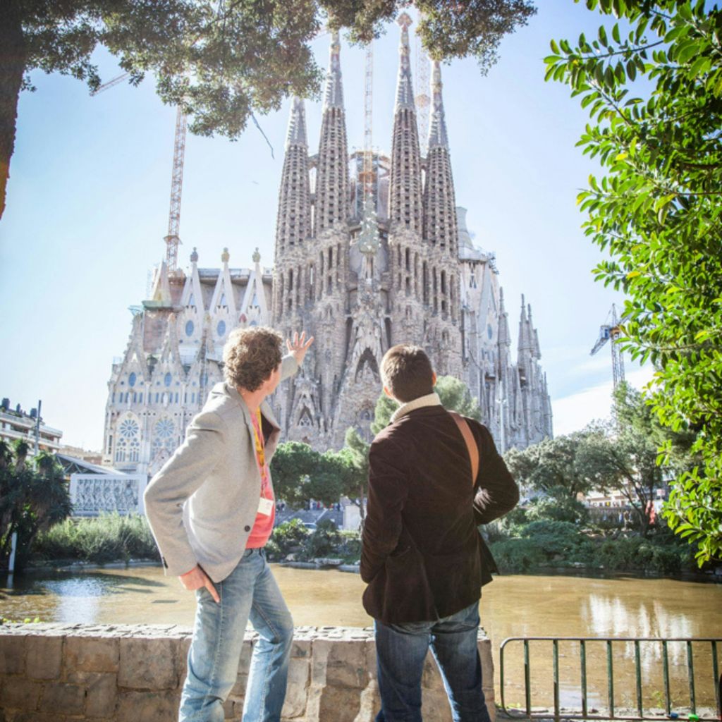 두 사람이 연못 근처에 서서 여러 개의 첨탑을 배경으로 커다란 대성당을 바라보고 손짓하고 있습니다.
