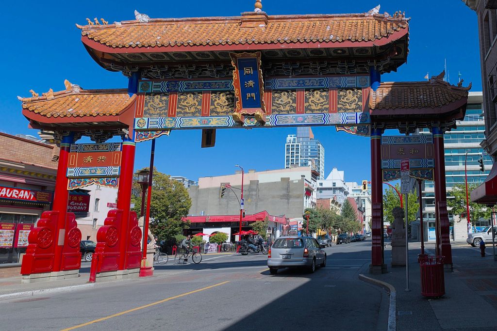 화창한 날 자동차와 건물을 배경으로 중국 전통 문이 길 위에 서 있습니다.