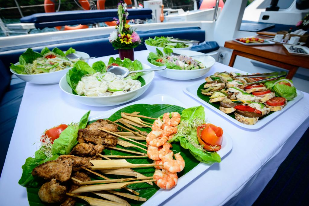 구운 고기 꼬치, 새우, 샐러드, 야채 등 다양한 요리가 꽃 중심이 되는 보트에 세팅되어 있습니다.