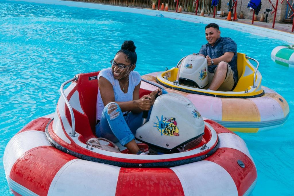 물웅덩이에서 범퍼보트를 타고 미소를 짓고 각 보트를 조종하는 두 사람이 즐거운 시간을 보내고 있습니다.