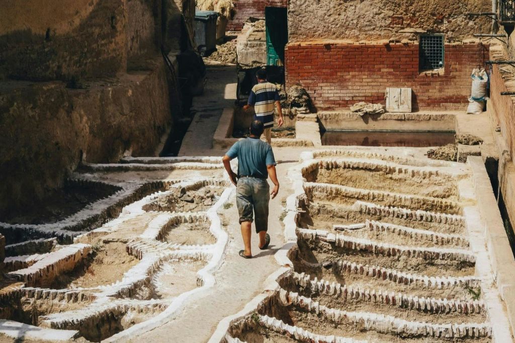 모로코의 전통 무두질장에서 고대 무두질 통 사이를 걷는 남성들