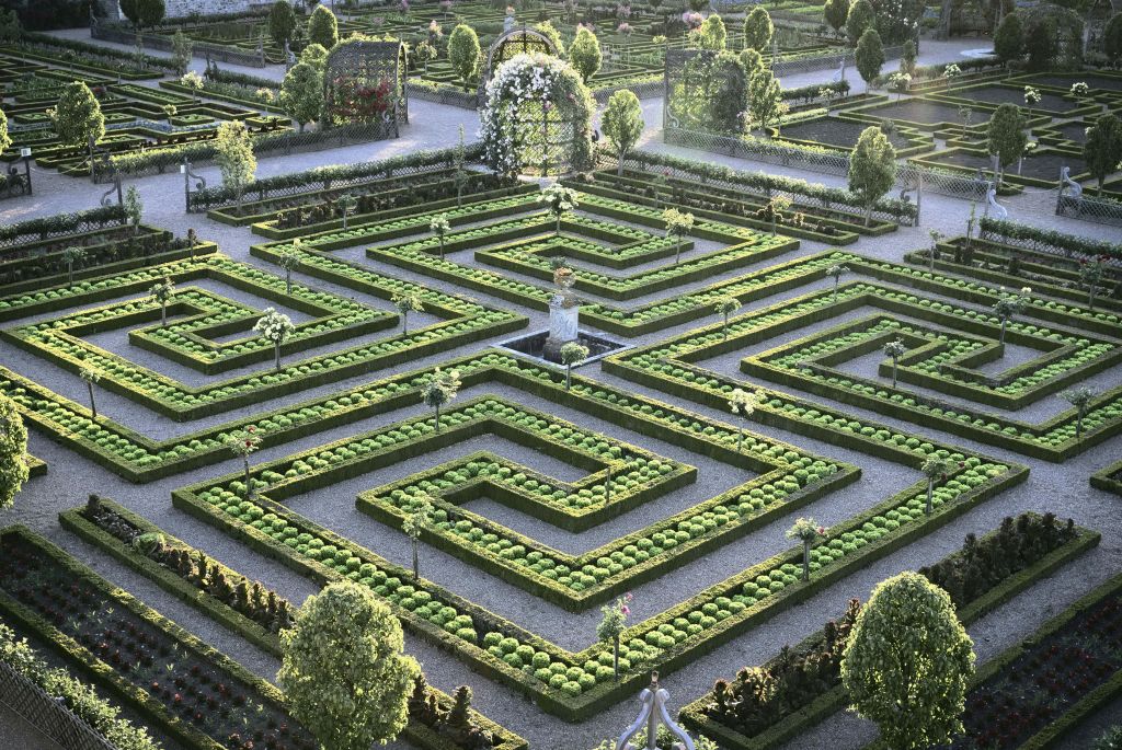 잘 다듬어진 울타리, 통로, 동상, 꽃과 녹지로 장식된 아치형 통로가 있는 복잡한 정원 미로.