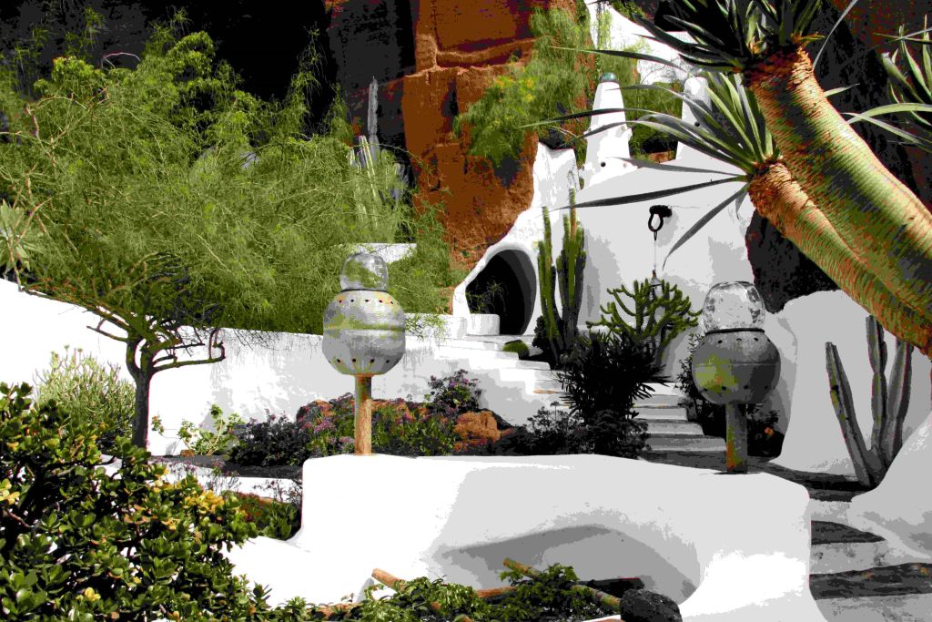 푸른 초목과 독특한 조각품으로 둘러싸인 계단이 있는 흰색 돔 모양의 건물입니다.