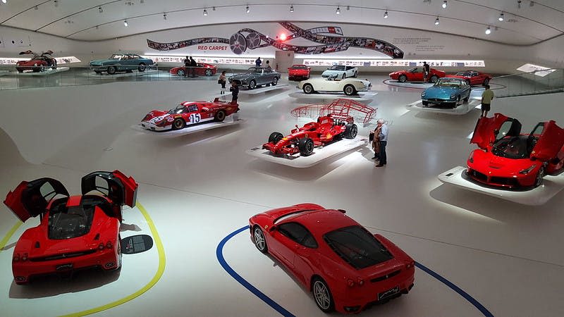 다양한 클래식 및 레이싱 카가 전시된 현대적인 박물관 전시관으로, 방문객들은 벽에 걸린 전시물과 전시물을 감상할 수 있습니다.