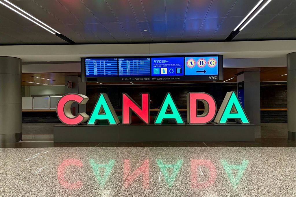 항공편 정보 화면을 배경으로 공항의 크고 화려한 '캐나다' 문자가 표시됩니다.
