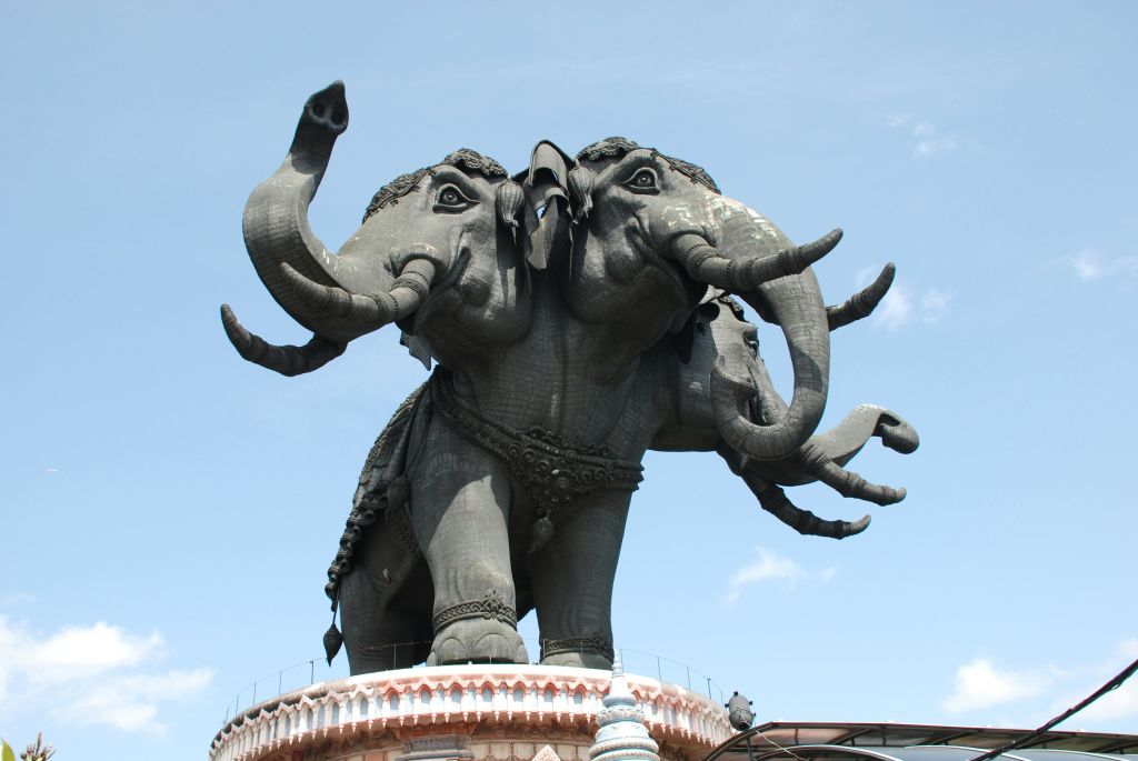 맑고 푸른 하늘 아래 장식 기지에 장착된 화려한 디테일이 돋보이는 머리 세 개 달린 코끼리의 커다란 동상.