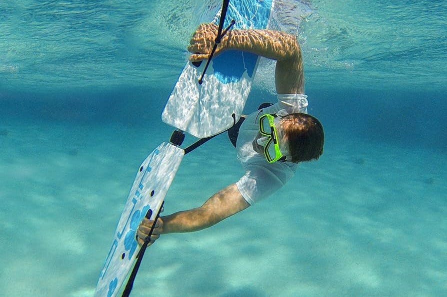 맑고 푸른 물 속에서 양손으로 커다란 지느러미 모양의 보드를 잡고 스노클링 마스크를 착용한 수중 사람.