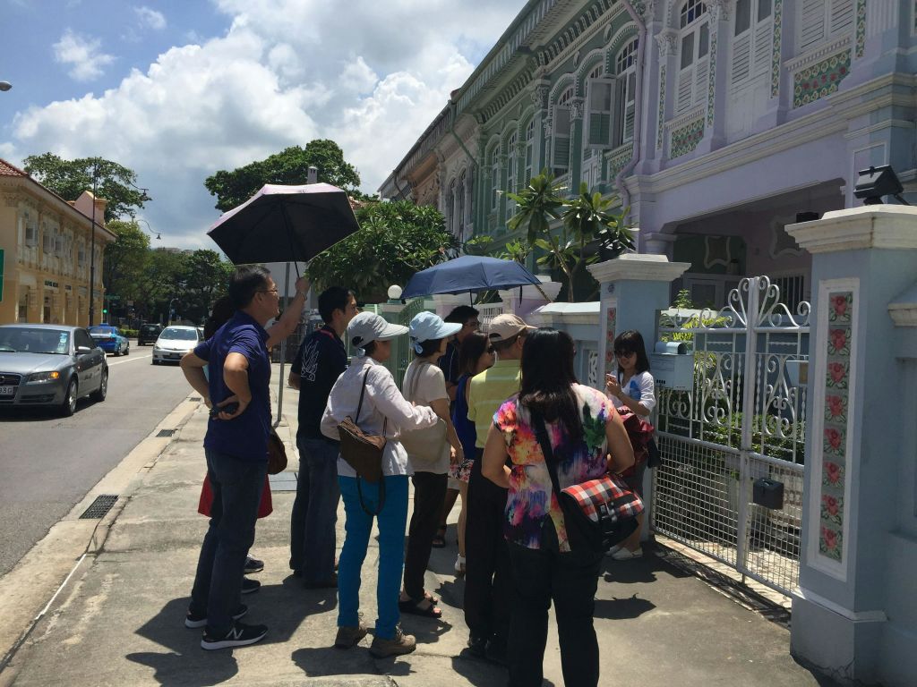 화창한 날, 우산을 든 사람들이 형형색색의 연립주택 바깥에 모입니다.