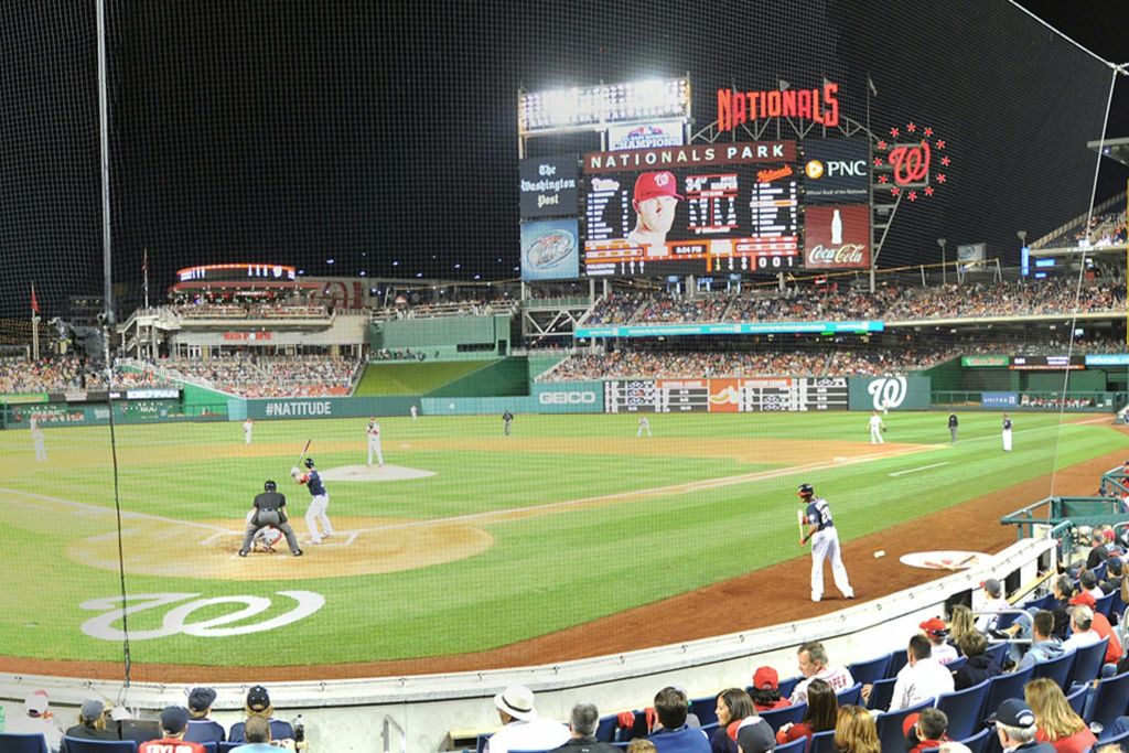내셔널스 파크 (Nationals Park) 의 야간 야구 경기로, 경기장의 선수들과 스탠드의 관중들이 경기를 관람합니다.