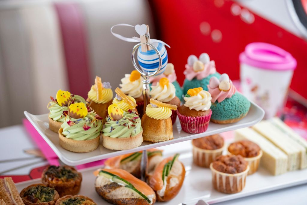 밝은 분위기의 컵케이크와 타르트 등 다채로운 색상의 페이스트리와 디저트가 층층이 쌓인 서빙 트레이에 담겨 있습니다.