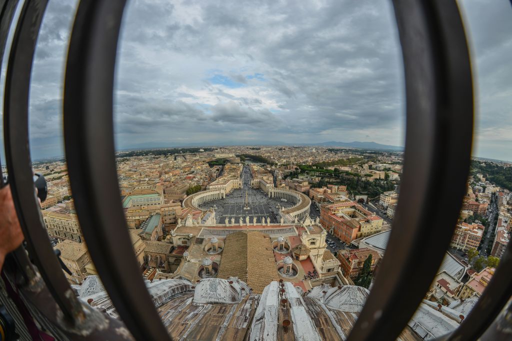 원형 콜로네이드가 있는 넓은 광장과 수많은 건물, 금속 난간으로 둘러싸인 흐린 하늘의 공중 전망.