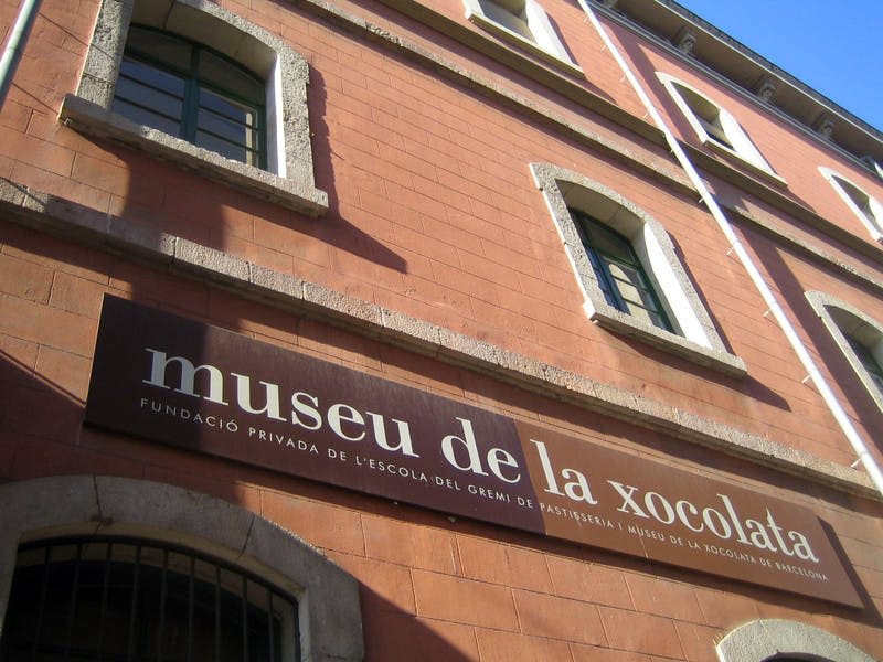 아치형 창문이 있는 붉은 벽돌 건물의 외관에는 "museu de la xocolata" 라고 적힌 팻말이 걸려 있습니다.
