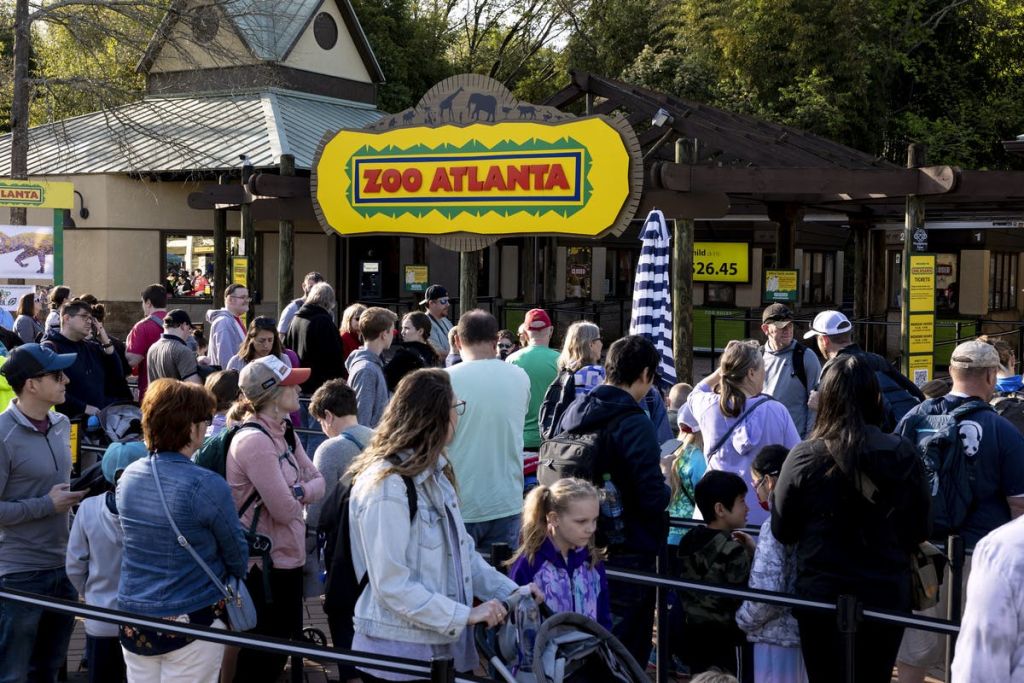 대문 위에 동물원의 팻말이 눈에 띄게 표시된 채로 애틀랜타 동물원 입구에 사람들이 모여들었습니다.